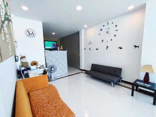 a living room with a couch and a clock on the wall at Nana hostel in Nakhon Phanom