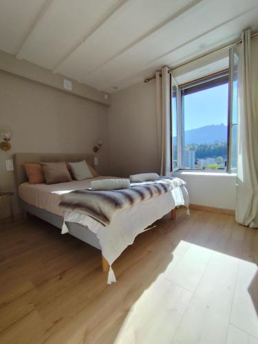 une chambre avec un grand lit et une grande fenêtre dans l'établissement Elegant studio between train station and city center, à Aix-les-Bains