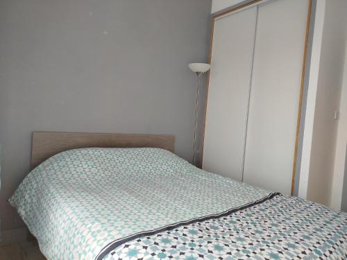 a bed in a bedroom next to a lamp at Appartement dans charmante petite résidence in Bergerac