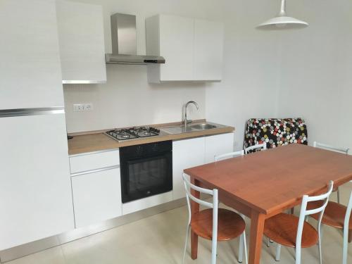 a kitchen with a wooden table with chairs and a sink at La Casina di Nonna Altea in Massa