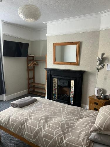 a bedroom with a bed with a fireplace and a mirror at Bourton House in Rugby