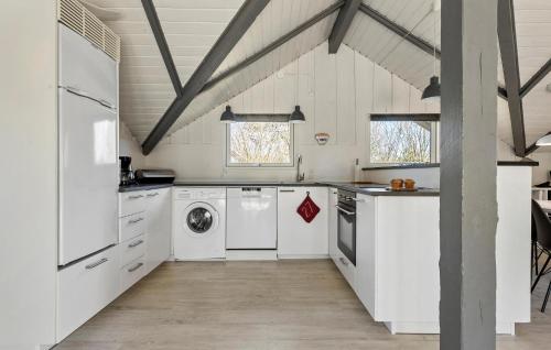 a kitchen with white cabinets and a washer and dryer at Holiday Home Fanø 57 in Sønderho