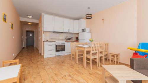 a kitchen with white cabinets and a table and chairs at Bursztynowe Osiedle Jantar, Sun & Snow in Jantar