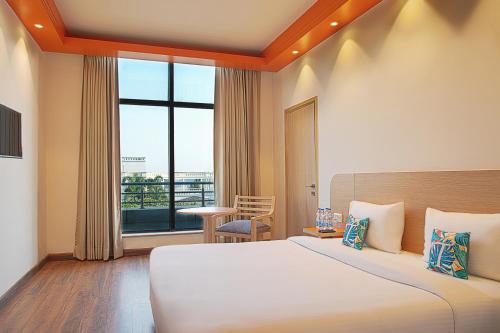 a hotel room with a bed and a large window at Nest By TreeHouse Bhiwadi in Bhiwadi