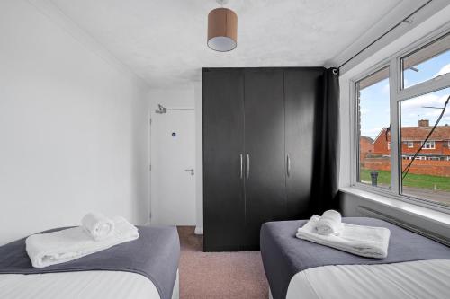 a bedroom with two beds and a large window at Elegant 5 Bedroom and 3 Bathroom Home in St Annes in Stanwell
