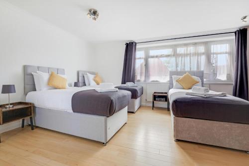 a bedroom with two beds and a window at Elegant 5 Bedroom and 3 Bathroom Home in St Annes in Stanwell