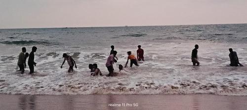 a group of people standing in the water at the beach at Srujana Beach Homestay in Gokarn