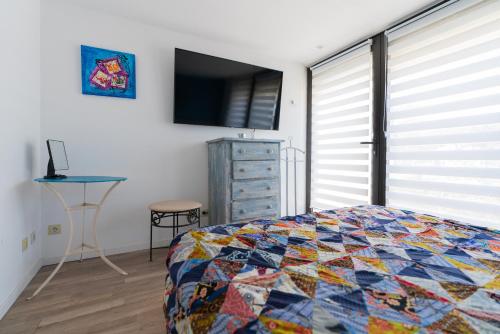 a bedroom with a quilt on a bed and a television at Grand T2 ensoleillé in La Grande-Motte