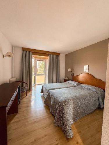 a bedroom with two beds and a large window at Puigcerda Park Hotel in Puigcerdà