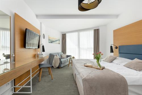ein Hotelzimmer mit einem großen Bett und einem Stuhl in der Unterkunft Seaside Park by Solarento in Kołobrzeg