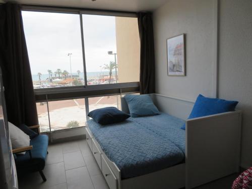 une chambre avec un lit avec des oreillers bleus et une fenêtre dans l'établissement Clématite - Vue port climatisé proche plage, à Saint-Cyprien