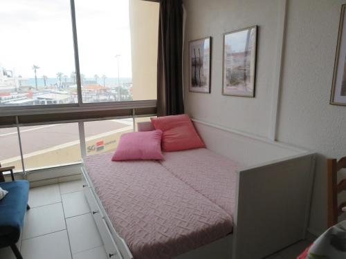- un lit avec des oreillers roses dans une chambre avec une fenêtre dans l'établissement Pivoine - Vue mer plage à 100m proche Espagne, à Saint-Cyprien