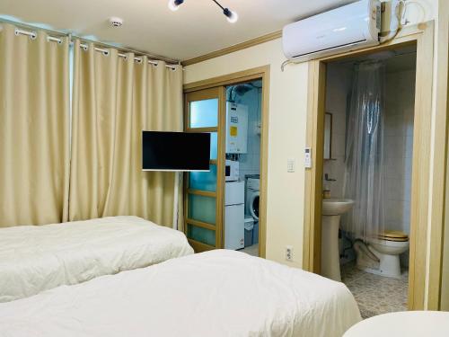 a hotel room with two beds and a television at Everville, Gaegeum Everville 304 #Stairs to 3rd floor in Busan