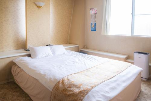 a bedroom with a large white bed with a window at Hotel Lucia at Maebashi Akagi in Maebashi
