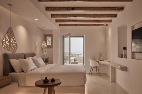 a bedroom with a bed and a table and a desk at Ovea Mykonos in Mikonos