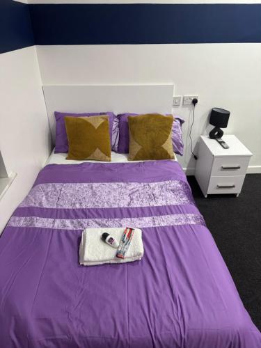 Una cama morada con una toalla encima. en Leicester Haven near Train Station, en Leicester