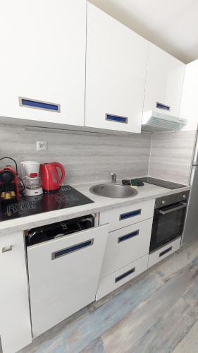 une cuisine avec des armoires blanches et un évier dans l'établissement L'Ecrin Bleu, Studio lumineux , Wifi & parking, à Villers-sur-Mer