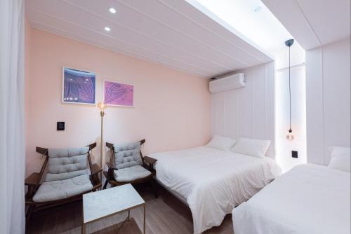 Un dormitorio con dos camas y una silla y una mesa. en Under the Tree, en Busan
