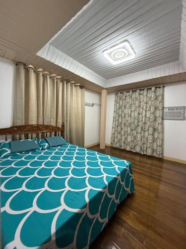 a bedroom with a bed with a blue and white comforter at Baloy Enyo-Noning in Baao