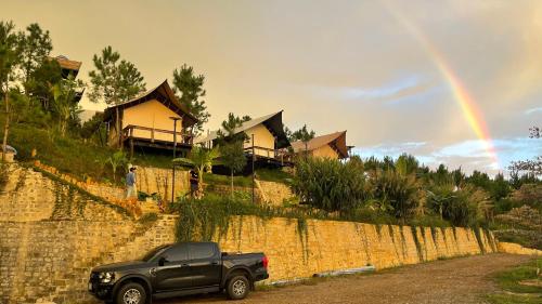 a truck parked on a road with a rainbow in the sky at ĐEN Hill Home The Glamping Luxury in Ðại Lào