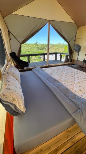 a bed in a tent with a view of the savannah at ĐEN Hill Home The Glamping Luxury in Ðại Lào