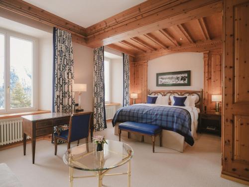 a bedroom with a bed and a desk and a table at Kulm Hotel St. Moritz in St. Moritz