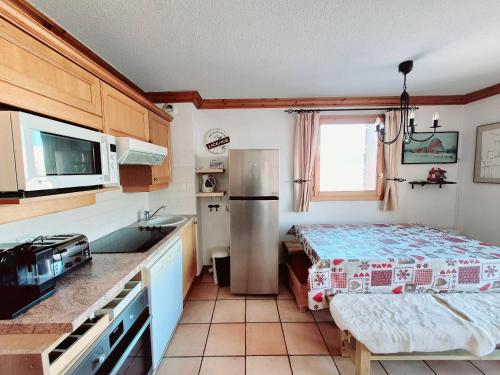 une cuisine avec un réfrigérateur et une table à l'intérieur dans l'établissement Appartement duplex au centre de la station, à 20m des pistes, 7 pers, WIFI, parking gratuit - FR-1-755-27, à Aime La Plagne