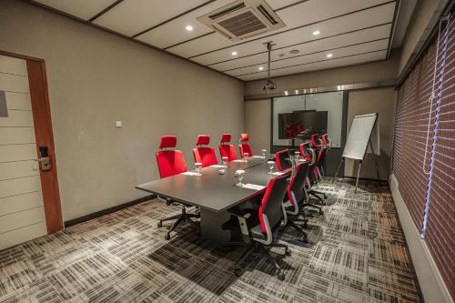 a conference room with a long table and red chairs at Hotel KIMAYA Slipi Jakarta By HARRIS in Jakarta