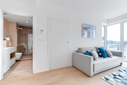 a white living room with a couch and a bathroom at Sea Collection by Marina Royale in Darłowo