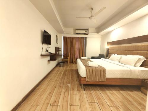 a bedroom with a large bed with a wooden floor at The Sky Comfort, Ahmedabad in Ahmedabad