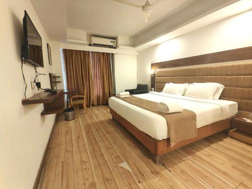 a hotel room with a bed and a television at The Sky Comfort, Ahmedabad in Ahmedabad