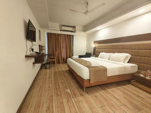 a bedroom with a large bed and a wooden floor at The Sky Comfort, Ahmedabad in Ahmedabad