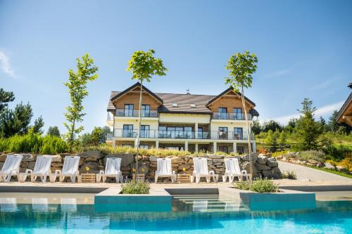 a large house with chairs and a swimming pool at Skalnica - Apartamenty w Bieszczadach nad Soliną in Berezka