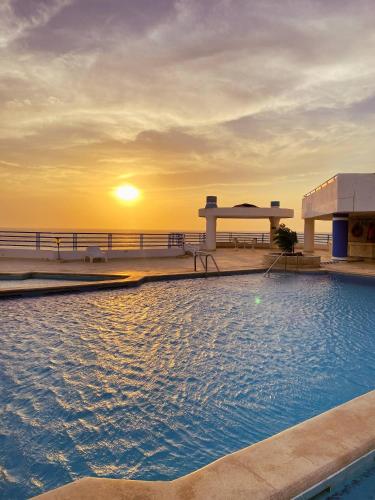 a swimming pool with the sunset in the background at Quiet apartment one block from the beach in Playa Bello Horizonte