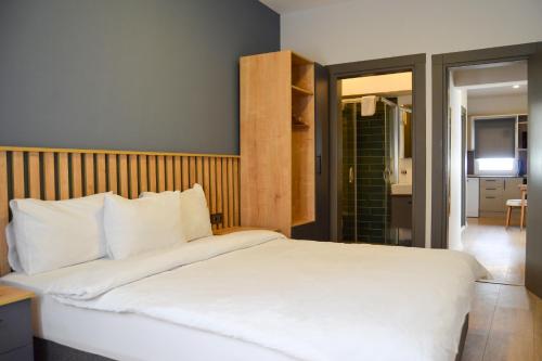 a bedroom with a large white bed and a bathroom at Loca Centre Suites in Bodrum City