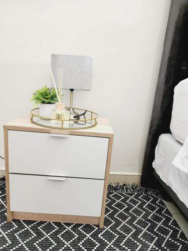 a nightstand with a lamp on it next to a bed at Eastern Road Executive Suites in Harare