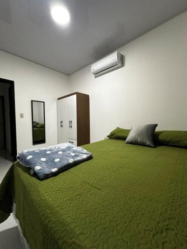 a bedroom with a large bed with a green comforter at Premium in Comayagua