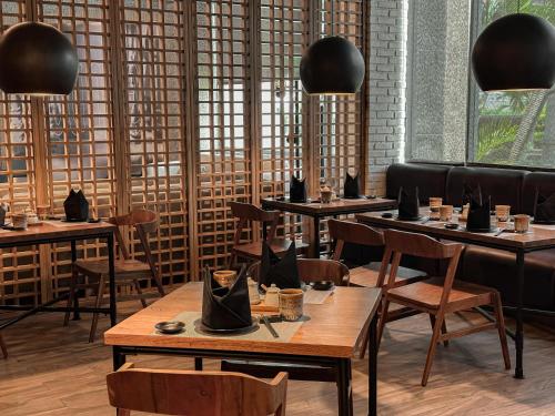 a restaurant with wooden tables and chairs and windows at Hotel KIMAYA Slipi Jakarta By HARRIS in Jakarta