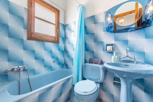 Un baño azul con lavabo, inodoro y bañera. en Dolce Far Niente, en Kato Korakiana