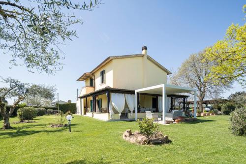 a house on a lawn with a tree stump at Casale Fattoria Benaris With Private Pool - Marsiliana in Marsiliana