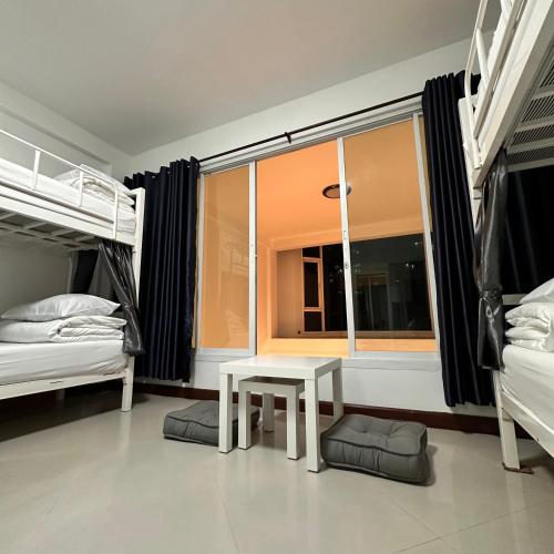 1 Schlafzimmer mit 2 Etagenbetten und einem Tisch vor einem Fenster in der Unterkunft 소다호스텔 Soda Hostel in Chiang Mai