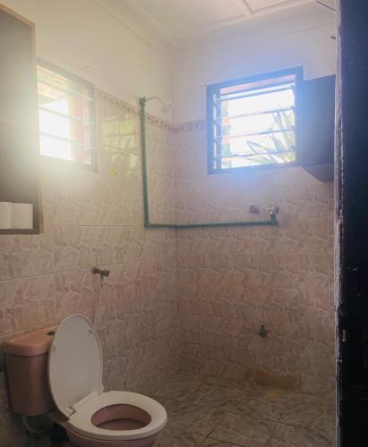 een badkamer met een toilet en een raam bij Serenity Eusy Diani in Ukunda