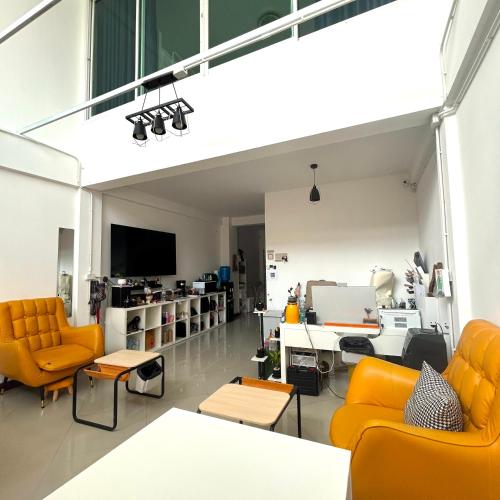 a living room with orange chairs and a tv at 소다호스텔 Soda HosteL in Chiang Mai