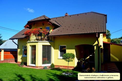 une maison jaune avec un balcon fleuri dans l'établissement Chalupa Riviéra a Apartmány Riviéra - Liptov Bešeňová, à Ružomberok