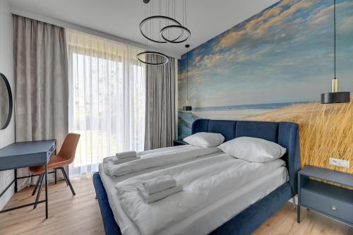 a bedroom with a blue bed with a painting on the wall at Comfort Apartments Botanika in Gdańsk