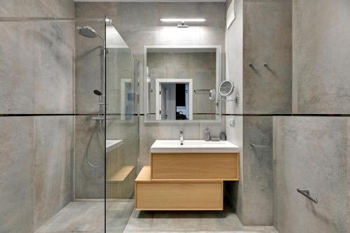 a bathroom with a sink and a shower with a mirror at Comfort Apartments Botanika in Gdańsk