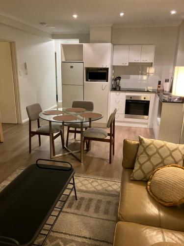 a living room with a couch and a table and a kitchen at Great Place in Perth CBD - 2 bedrooms - parking included in Perth