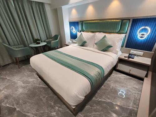 a hotel room with a large bed and a table at Hotel Prime Suites Airoli in Navi Mumbai
