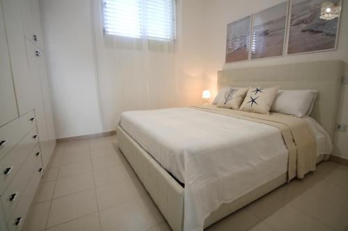 una camera bianca con un grande letto bianco con cuscini di Giada a Baia Verde