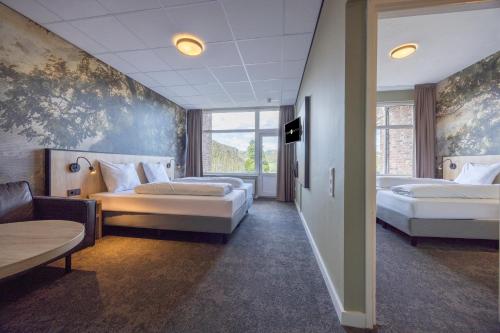 a hotel room with two beds and a couch at Fletcher Hotel Restaurant Bon Repos in Noorbeek